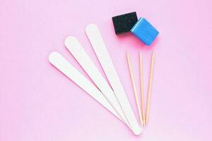 Different abrasive nail polishing files and wooden sticks on pink background. Manicure and pedicure instruments set . Cosmetic accessories hygiene equipment. Beauty spa salon, hand care concept photo