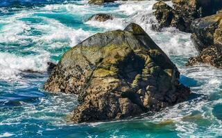 Surfer waves turquoise blue water rocks cliffs boulders Puerto Escondido. photo