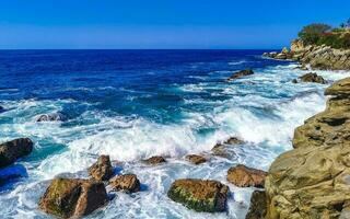 Surfer waves turquoise blue water rocks cliffs boulders Puerto Escondido. photo