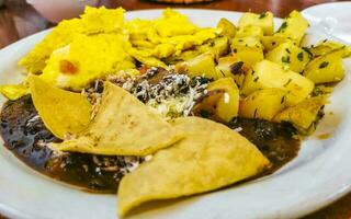 Mexican omelet eggs black beans potatoes nachos on white plate. photo