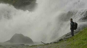 caucasico viaggiatore con zaino su il bordo di il cascata. lento movimento metraggio video