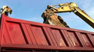 graafmachine bezig met laden zwaar plicht dump vrachtauto met een bodem. bouw plaats. langzaam beweging filmmateriaal. video