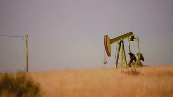 pétrole pompe sur Californie prairie. scénique industriel le coucher du soleil. pétrole industrie thème avec pompage unité. video