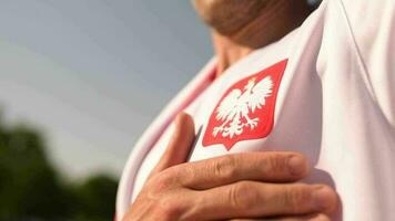 polaco fútbol americano ventilador orgulloso a ser parte de el partido acuerdo su mano en el corazón cerca polaco nacional símbolo. video