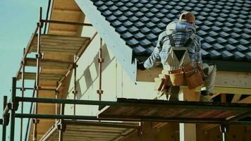 Roof Tiles Covering. Caucasian Contractor in His 30s Working on a Scaffolding. video