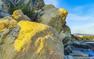 Surfer waves turquoise blue water rocks cliffs boulders Puerto Escondido. photo