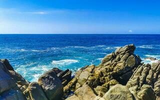 Surfer waves turquoise blue water rocks cliffs boulders Puerto Escondido. photo