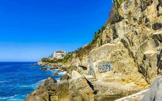 Surfer waves turquoise blue water rocks cliffs boulders Puerto Escondido. photo