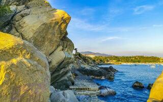 Surfer waves turquoise blue water rocks cliffs boulders Puerto Escondido. photo