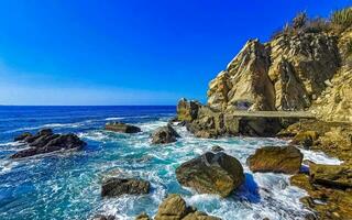 Surfer waves turquoise blue water rocks cliffs boulders Puerto Escondido. photo