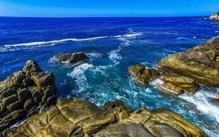 Surfer waves turquoise blue water rocks cliffs boulders Puerto Escondido. photo