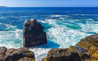 Surfer waves turquoise blue water rocks cliffs boulders Puerto Escondido. photo