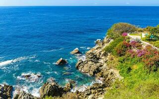 Surfer waves turquoise blue water rocks cliffs boulders Puerto Escondido. photo