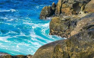 Surfer waves turquoise blue water rocks cliffs boulders Puerto Escondido. photo