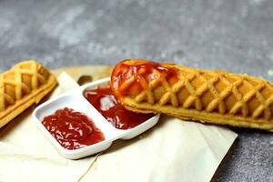 Corn dogs waffle and ketchup on a gray table photo