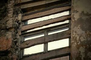 antiguo ventana clavado con de madera tablones de abandonado Envejecido casa con peladura yeso en ladrillos foto