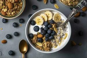 Bowl of greek yogurt with oatmeal granola, banana, blueberry, nuts, chia seeds and honey on gray table. Top view, generate ai photo