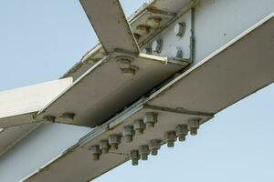 Bolts and nuts on metal plates of steel structure of heavy duty straight crossbar of frame and bridge support photo