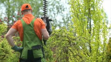 caucasico giardiniere nel il suo 30s con benzina trimmer energia giardino attrezzo. video