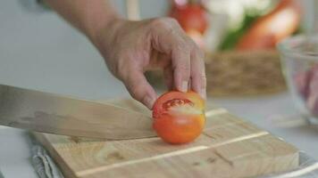 cozinhando - chef mãos estão corte tomates em a cortar borda dentro a cozinha. video