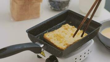 brood croutons in een ei zijn gebakken in een pan. detailopname. gebakken brood plakjes met melk voor ontbijt. video