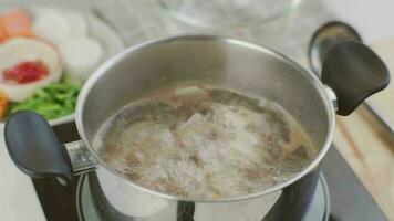 cucinando dello chef mani siamo mettendo Maiale costolette nel un' pentola di bollente acqua nel il cucina. preparazione Maiale azione con verdure brodo un' pentola. video