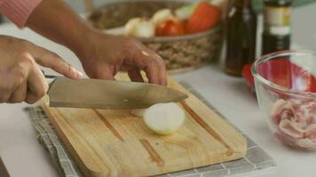 mulher mão usando faca para cortar branco cebola em de madeira corte borda. mulher preparando Comida dentro a cozinha às lar. video