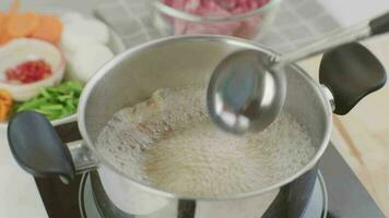 cozinhando chef mãos estão colocando carne de porco costelas dentro uma Panela do ebulição água dentro a cozinha. preparando carne de porco estoque com legumes irmão uma Panela. video