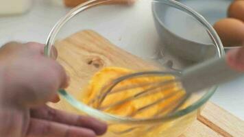 Woman beating eggs in a glass bowl. Young woman cooking in the kitchen. video