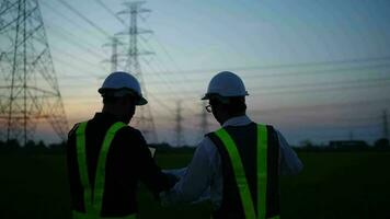 Two male electrical engineers dressed safe to inspect the site. high voltage pole. video