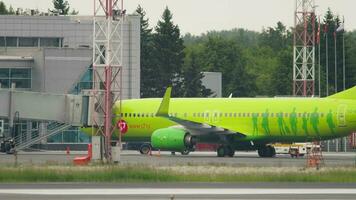 NOVOSIBIRSK, RUSSIAN FEDERATION JUNE 10, 2020 - Green airplane S7 Airlines stands at the airport with a boarding bridge. Concept tourism. Boarding passengers through the telescopic gangway video