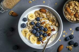 Bowl of greek yogurt with oatmeal granola, banana, blueberry, nuts, chia seeds and honey on gray table. Top view, generate ai photo