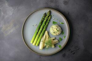 Traditional Bavarian white asparagus served with wild garlic and almond butter close-up on a Nordic design plate with copy space, generate ai photo