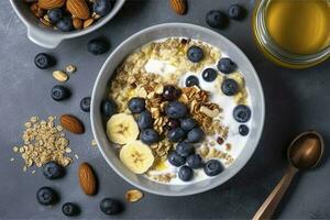 Bowl of greek yogurt with oatmeal granola, banana, blueberry, nuts, chia seeds and honey on gray table. Top view, generate ai photo