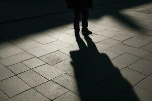 oscuro sombra de un solitario persona en el suelo en el calle. desconocido con un cigarrillo. ansiedad, depresión, soledad, temor concepto, generar ai foto