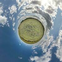 net zero emissions text concept image against green tiny planet in blue sky with beautiful clouds photo