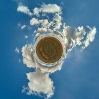 tiny planet in blue sky with beautiful clouds. Transformation of spherical panorama 360 degrees. Spherical abstract aerial view. Curvature of space. photo