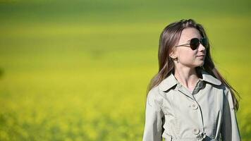 Young Cute Girl With Sunglasses On Standing In Yellow Windy Meadow Smiling And Looking Around video