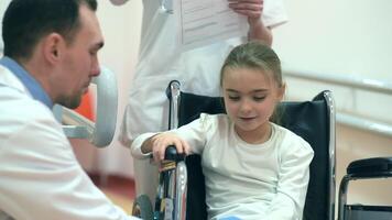 feliz cadeira de rodas Desativado menina com dela médicos. hospital instalação complexo. video