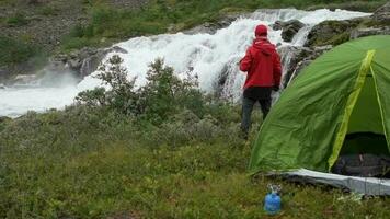 campingplats i de vild. caucasian turist njuter de se i främre av hans tält. video