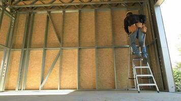 caucásico construcción trabajador en un escalera. acero marco casa edificio video