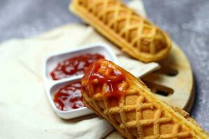 Corn dogs waffle and ketchup on a gray table photo