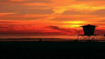 puesta de sol a el lado del mar California playa con Salvavidas torre. video