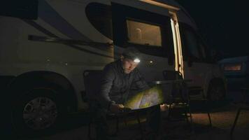 Hommes avec lampe de poche en train de lire carte à la recherche pour meilleur les sentiers. camping RV parc. video