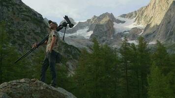 Photographer with Camera on a Boulder Enjoying Scenic Mountain Vista video