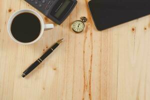 fuente bolígrafo y caliente café en madera mesa.oficina herramienta. foto