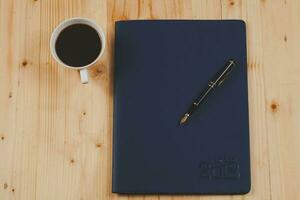 personal organizer or planner with fountain pen and hot coffee on wood table. photo