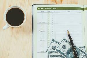 personal project planner with fountain pen and hot coffee on wood table. photo