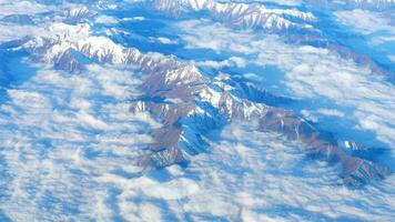 hermosa vista a través de la ventana del avión, avión volando sobre las montañas con nubes. territorio chino. video
