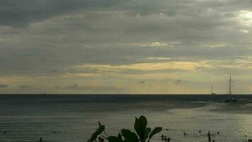 Scenic seascape timelapse on Phuket island at dusk with boats, yachts and people on the beach and surfing in water video